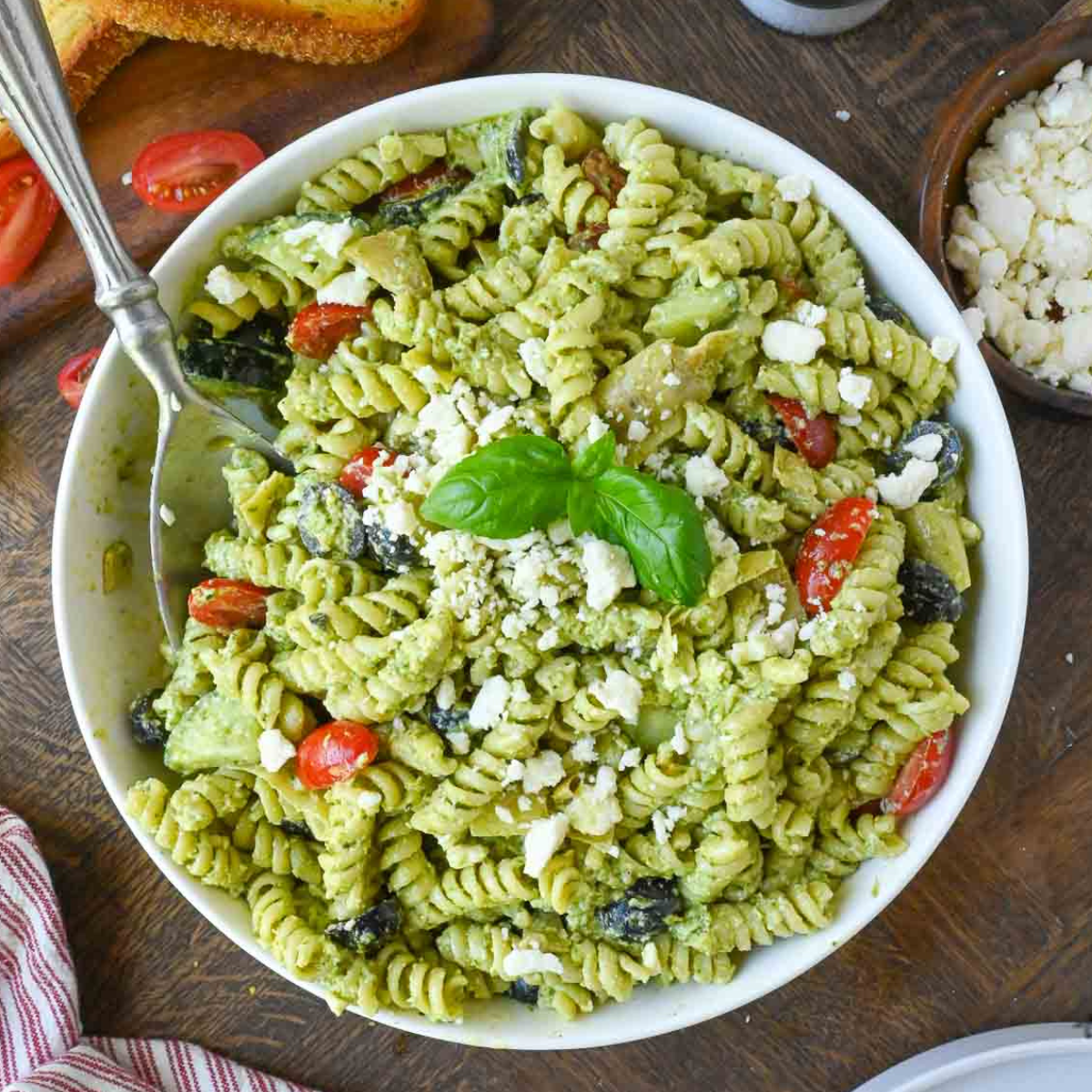 A close up of creamy pesto pasta in a white bowl.