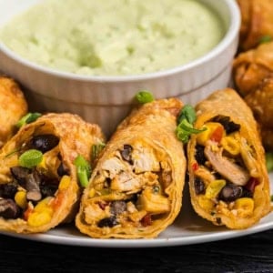 A plate of tex mex egg rolls with dipping sauce.