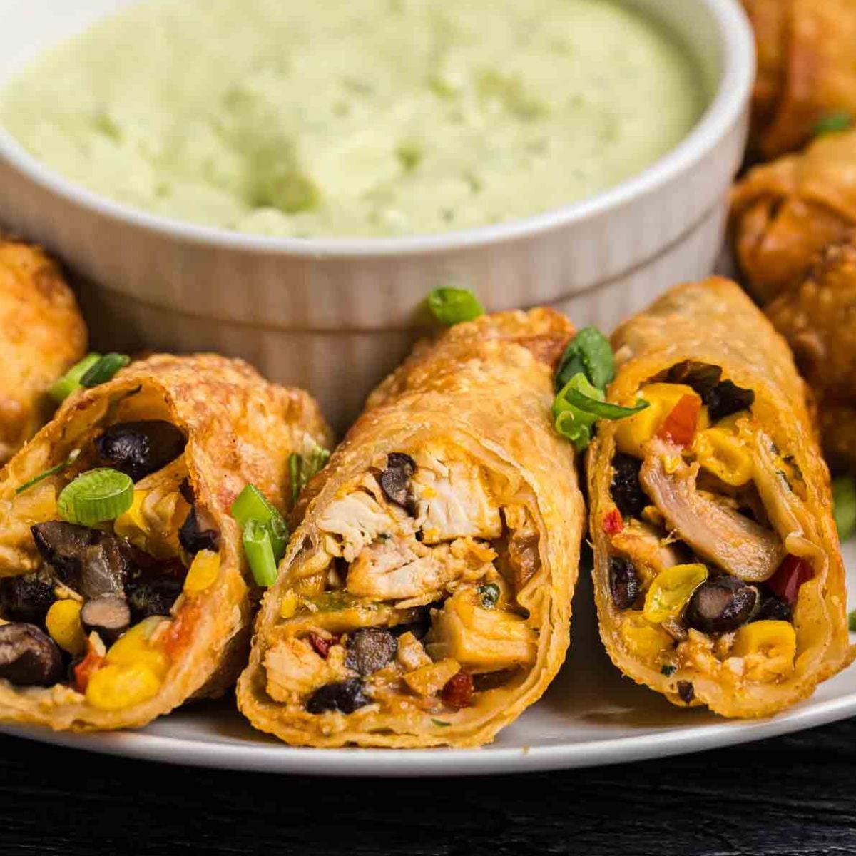 A plate of tex mex egg rolls with dipping sauce.