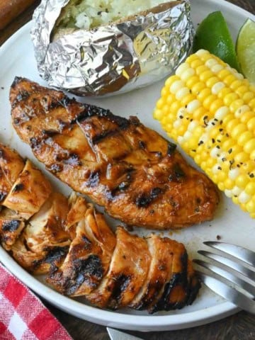 Chipotle honey chicken served with corn and a baked potato.
