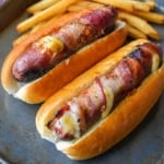 Bacon wrapped hot dogs with french fries on the side.