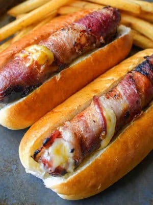 Bacon wrapped hot dogs with french fries on the side.