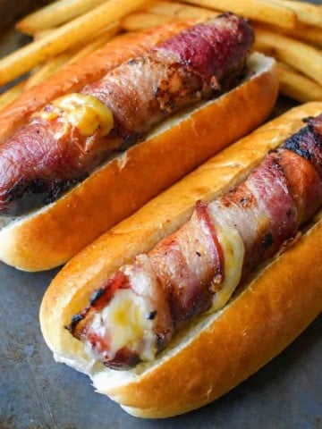 Bacon wrapped hot dogs with french fries on the side.