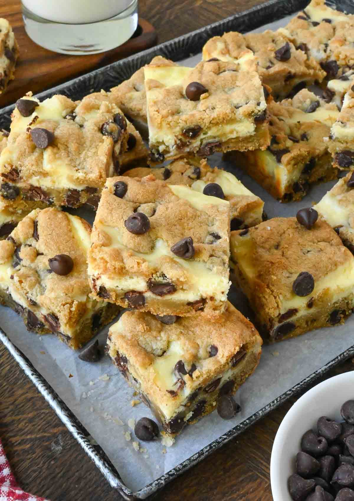 A baking tray with stacks of chocolate chip cookie cheesecake bars.