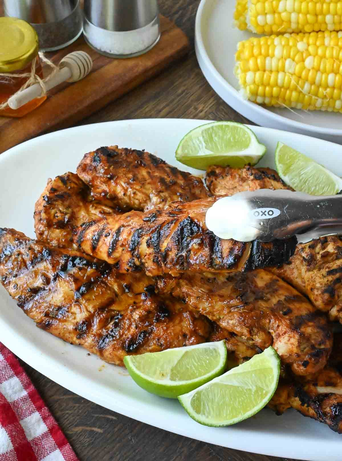 Using tongs to pick up a piece of copycat chipotle honey chicken.