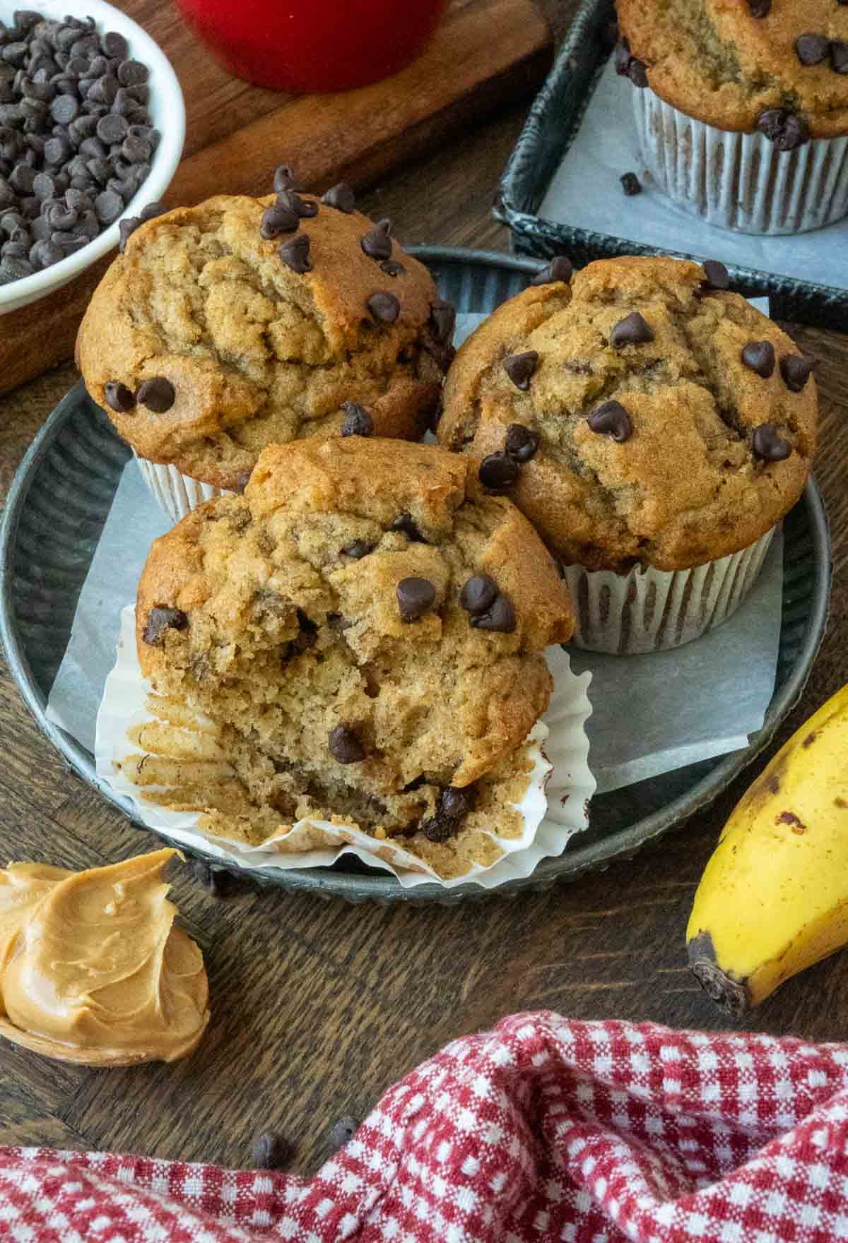A plate of three peanut butter banana muffins, one with a bite taken from it.