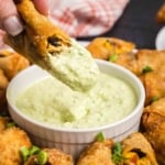 Dipping a southwest egg roll into creamy avocado sauce.