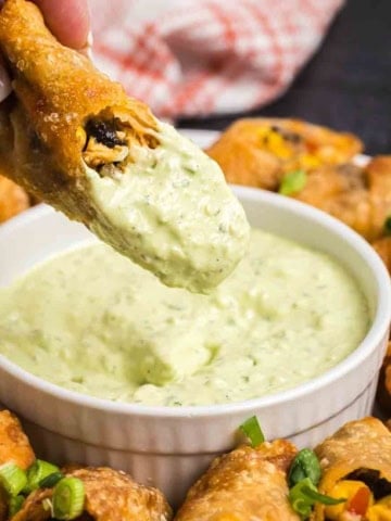 Dipping a southwest egg roll into creamy avocado sauce.