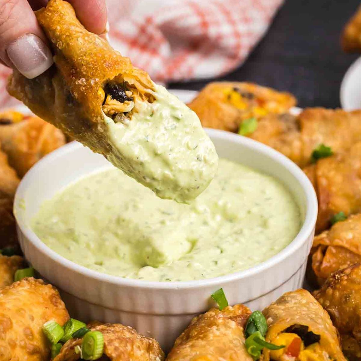 Dipping a southwest egg roll into creamy avocado sauce.