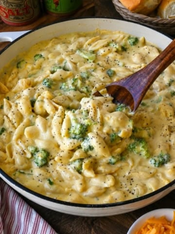 Mixing broccoli mac and cheese with a wooden spoon.