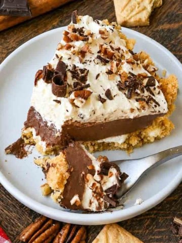 A plate with a slice of possum pie and a fork that's taken one scoop from the front of the slice.