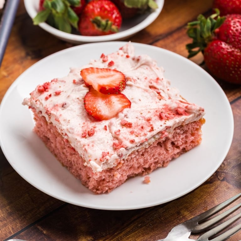 A close up of a slice of strawberry sheet cake on a plate.