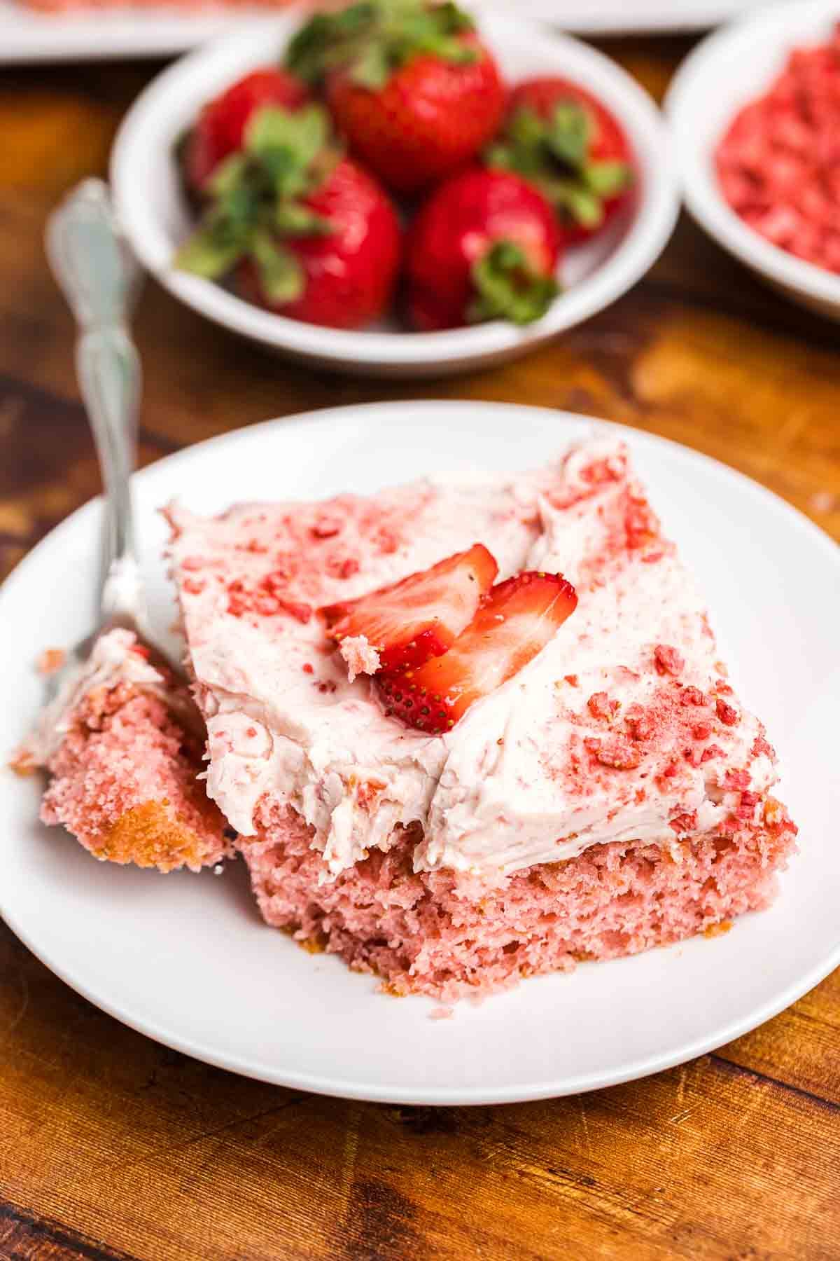 A plate of strawberry sheet cake with a fork.