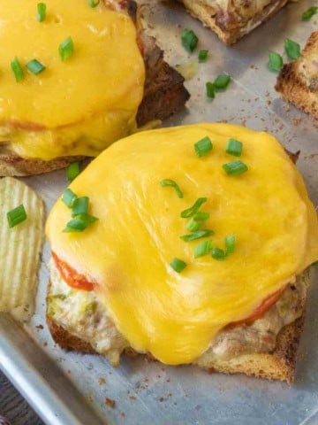Several open face tuna melts on a baking sheet.