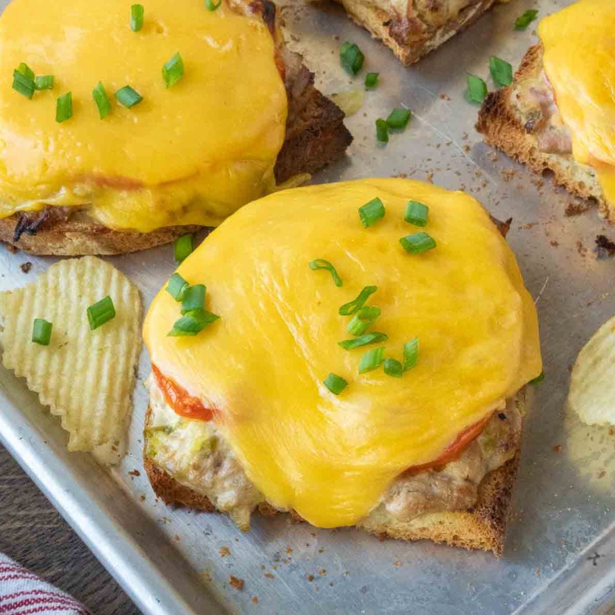 Several open face tuna melts on a baking sheet.