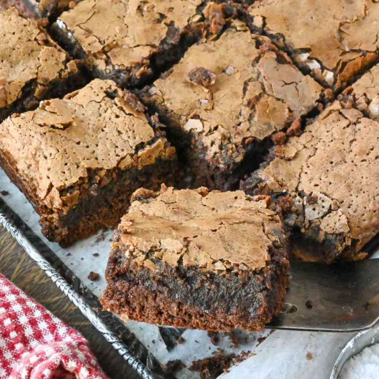 A close up of a slice gooey chocolate butter cake being lifted from a baking pan.