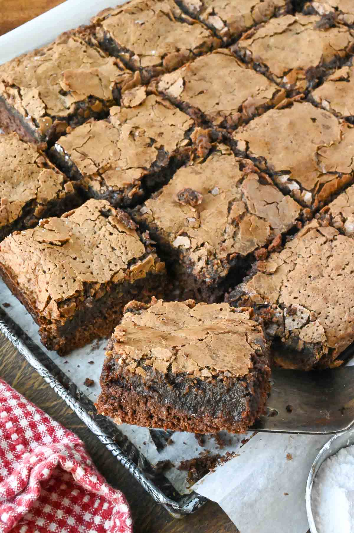 Using a spatula to lift a piece of chocolate butter cake out of a baking pan.