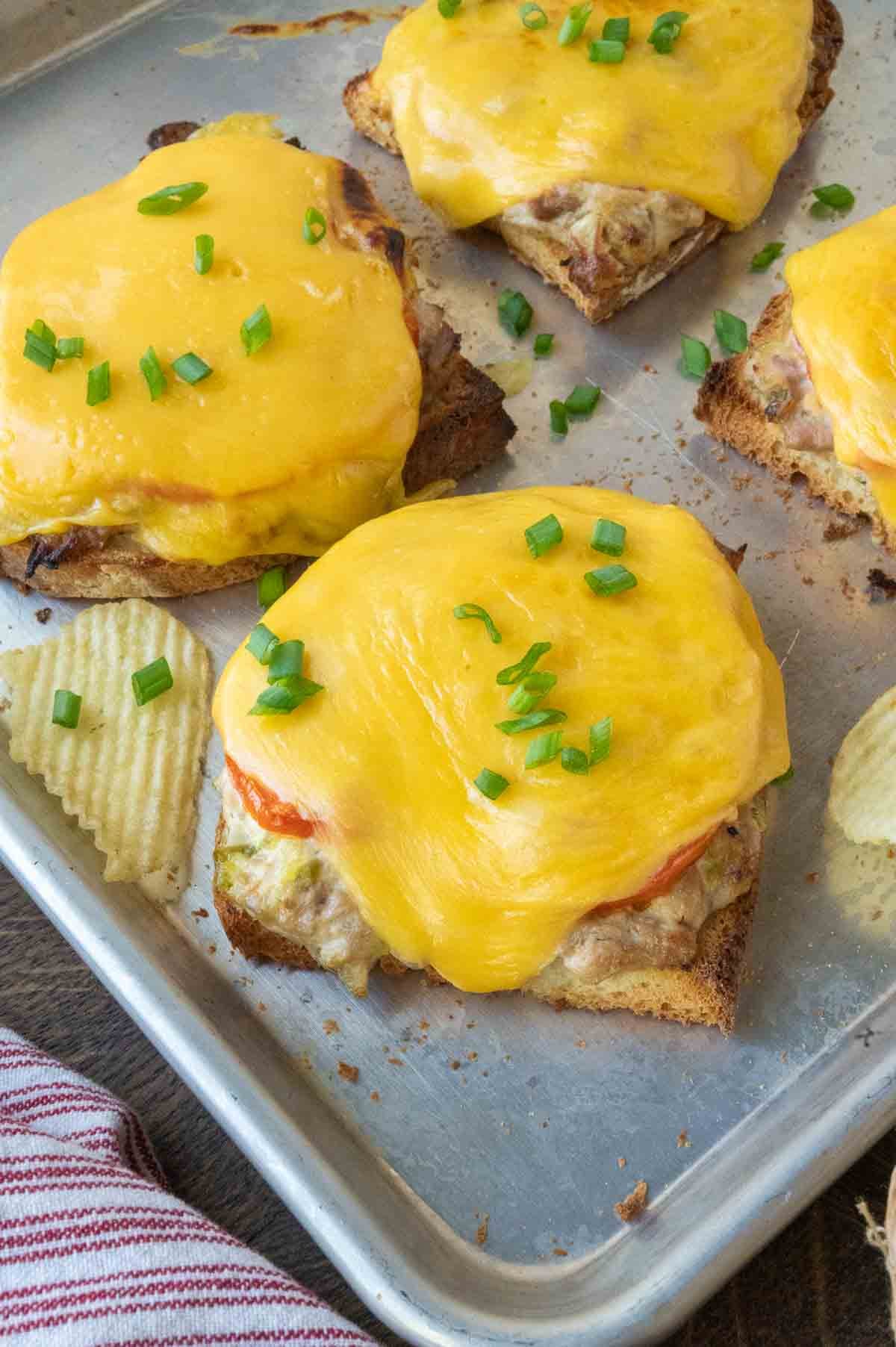 Four open faced tuna melts on a baking sheet.