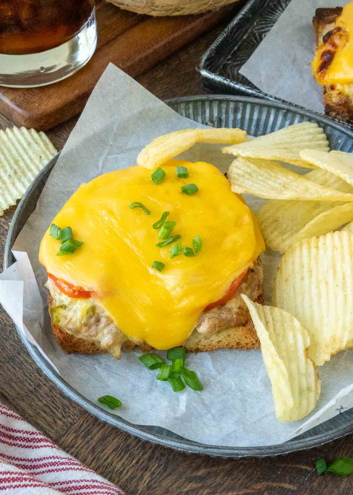 Tuna melt sandwich on a plate with potato chips.