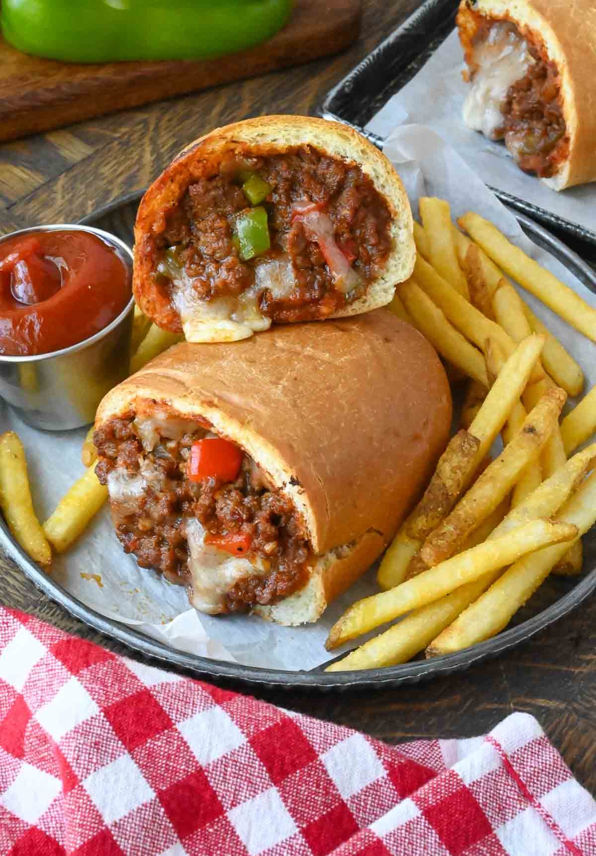 A basket of stuffed sloppy joe stuffed rolls in a basket with french fries and ketchup.