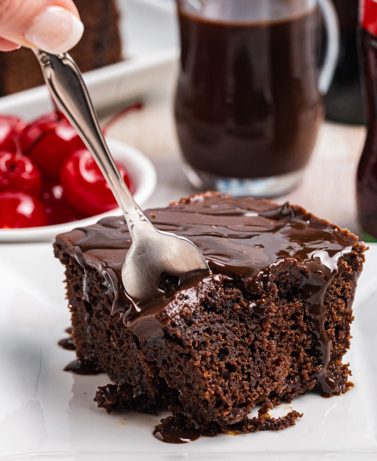 Coco cola cake on a plate with a fork taking a bite out of it.