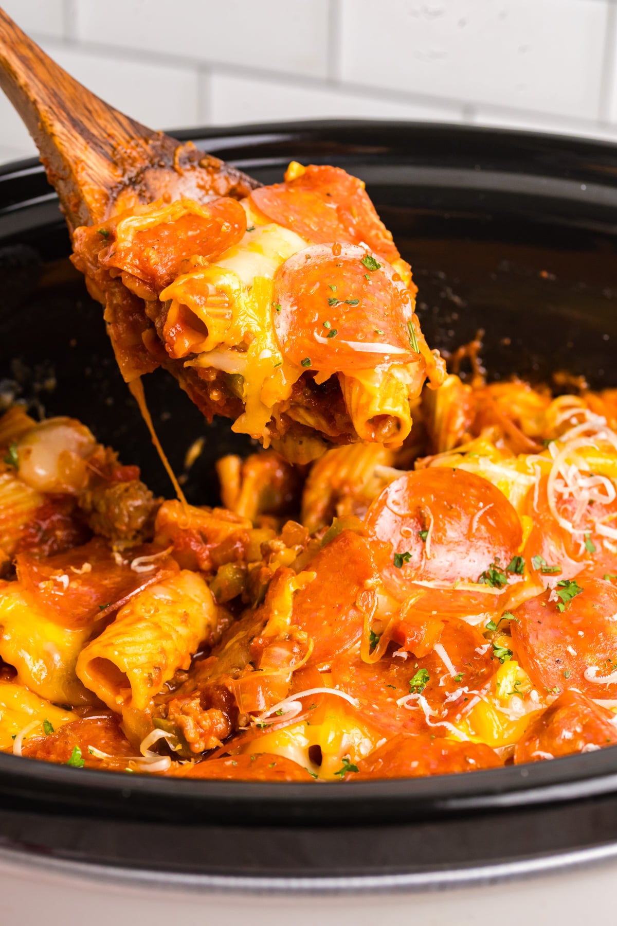 A wooden spoon scooping up some pizza casserole.