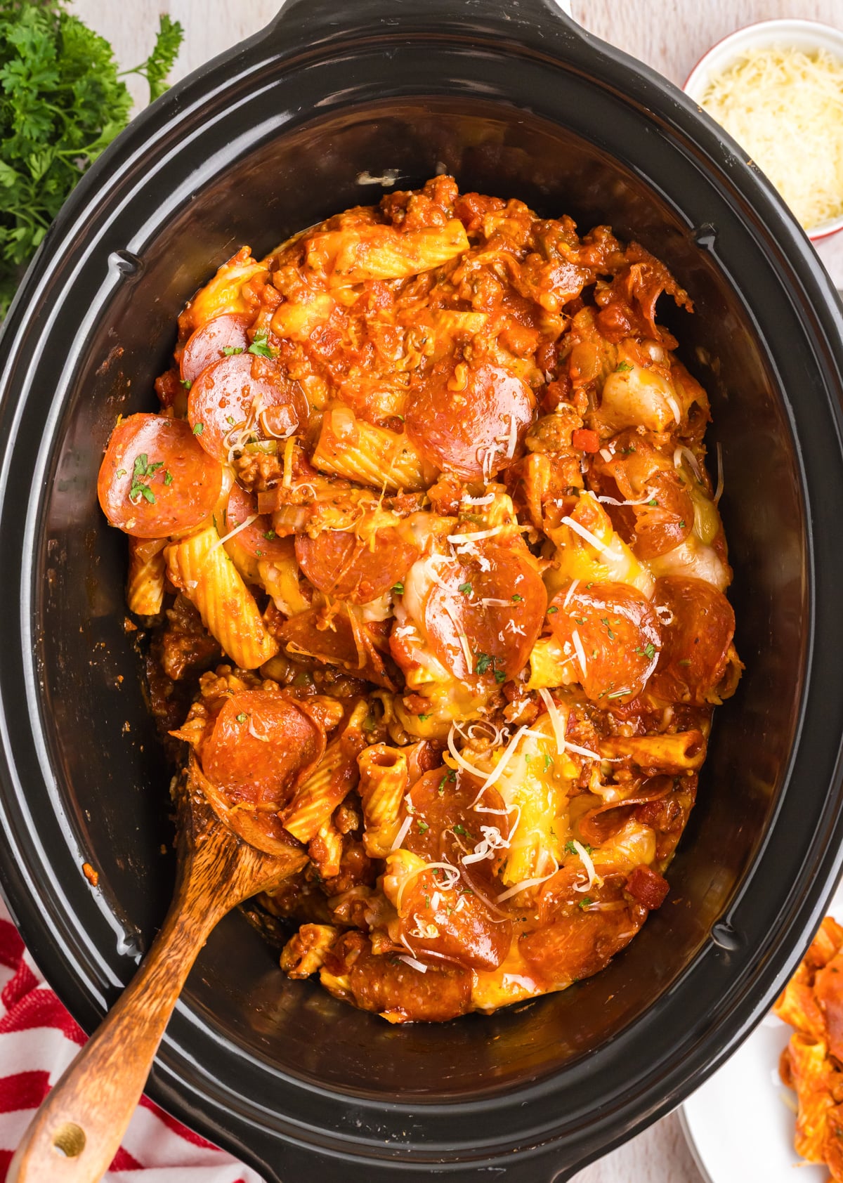 Crock pot pizza casserole in a slow cooker with a wooden spoon.
