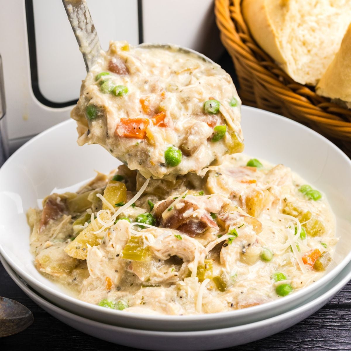 A ladle pouring some chicken stew into a bowl.