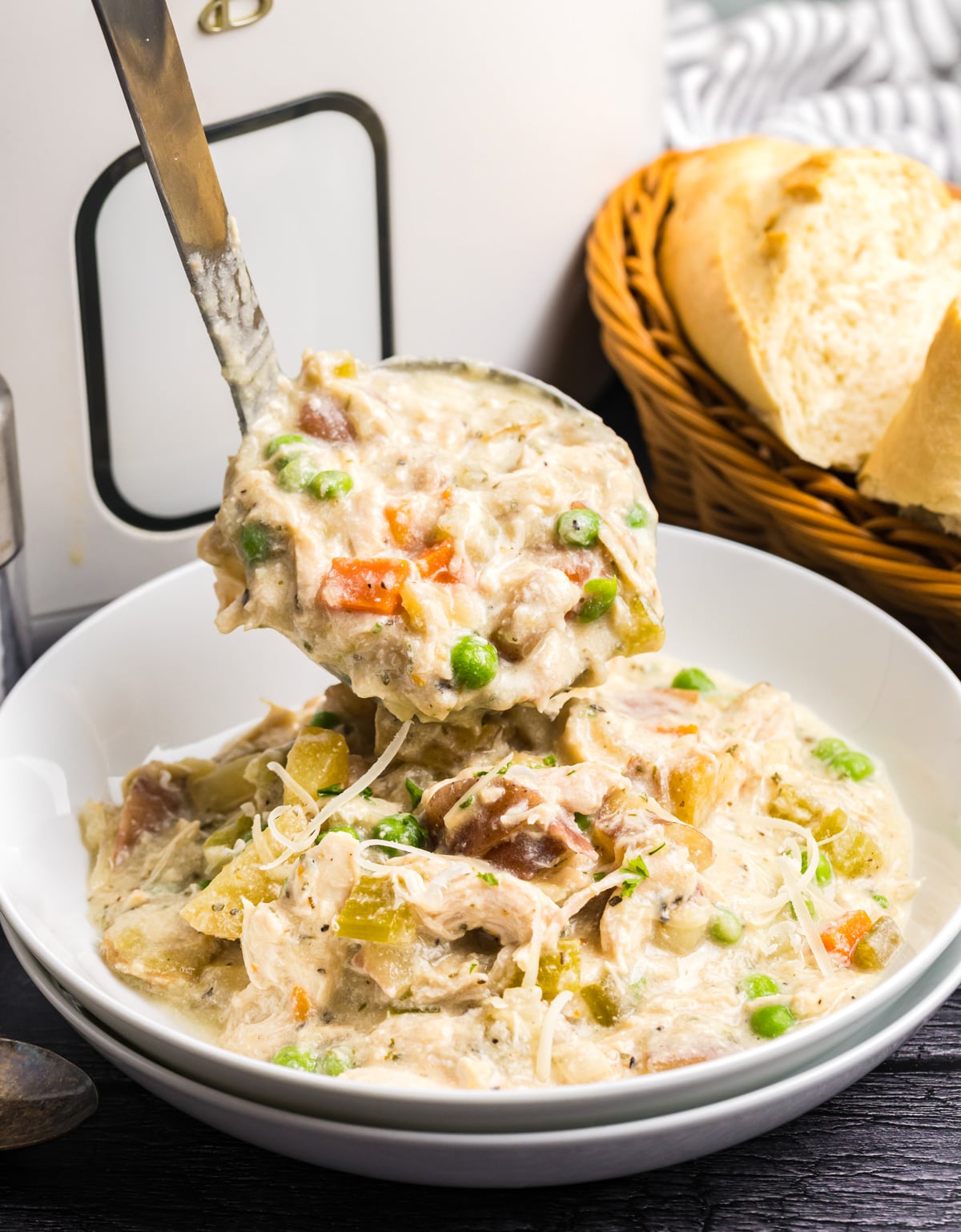 A ladle pouring some chicken stew into a bowl.